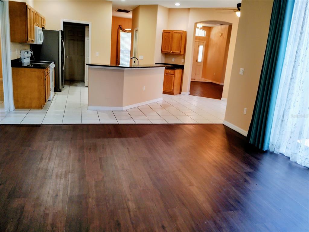 A kitchen with wood cabinets and a breakfast bar overlooks a dark wood-floored living area — 4509 30TH LANE E, BRADENTON, FL