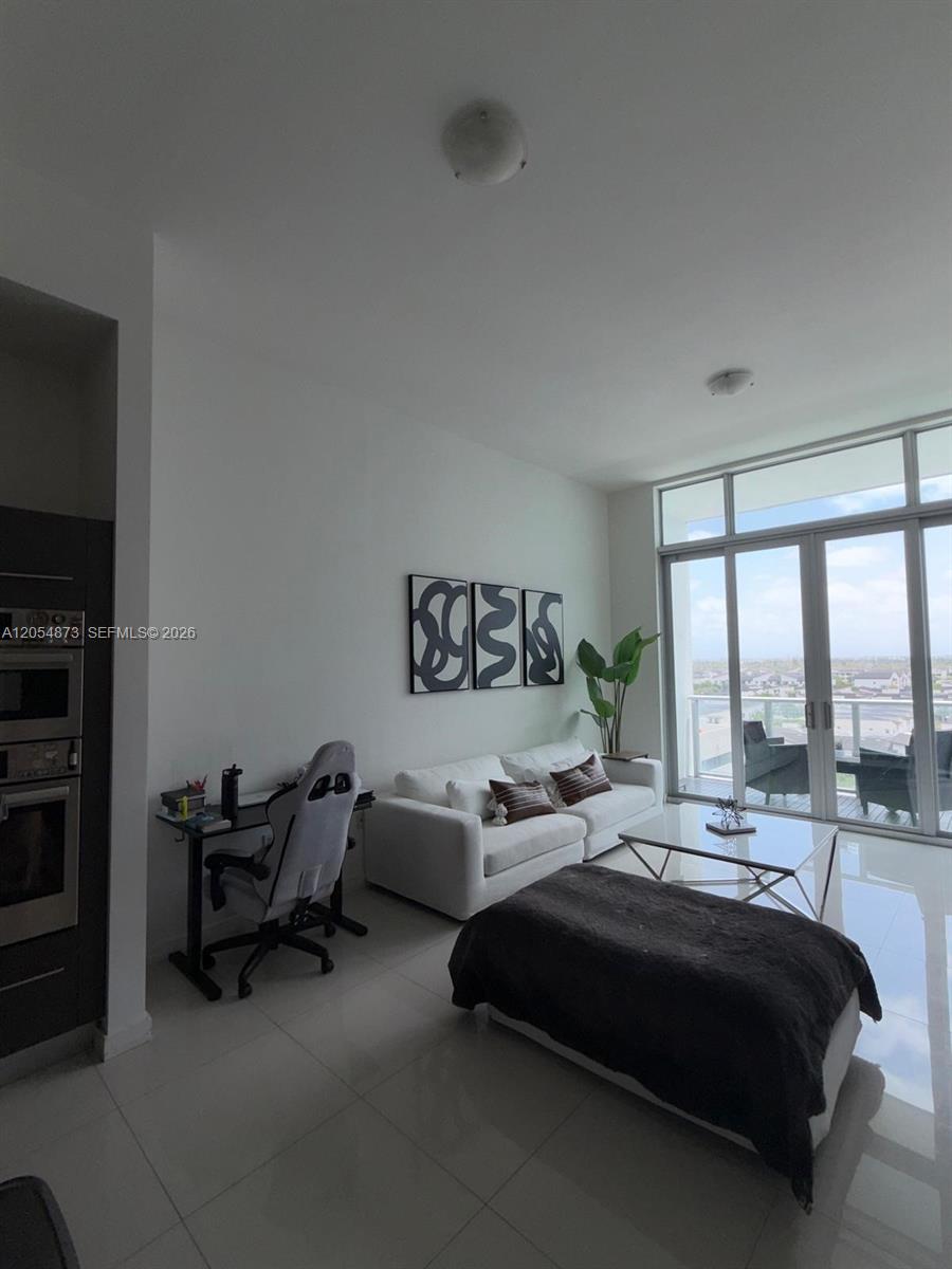 A modern living room features white tile floors, a white sofa, and a glass desk — 7825 NW 107th Ave # 818, Doral FL 33178, DORAL, FL