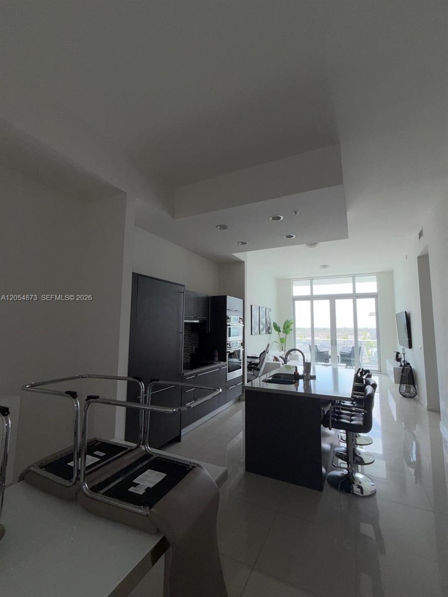 A modern kitchen features dark cabinetry, a central island with bar seating, and floor-to-ceiling windows — 7825 NW 107th Ave # 818, Doral FL 33178, DORAL, FL