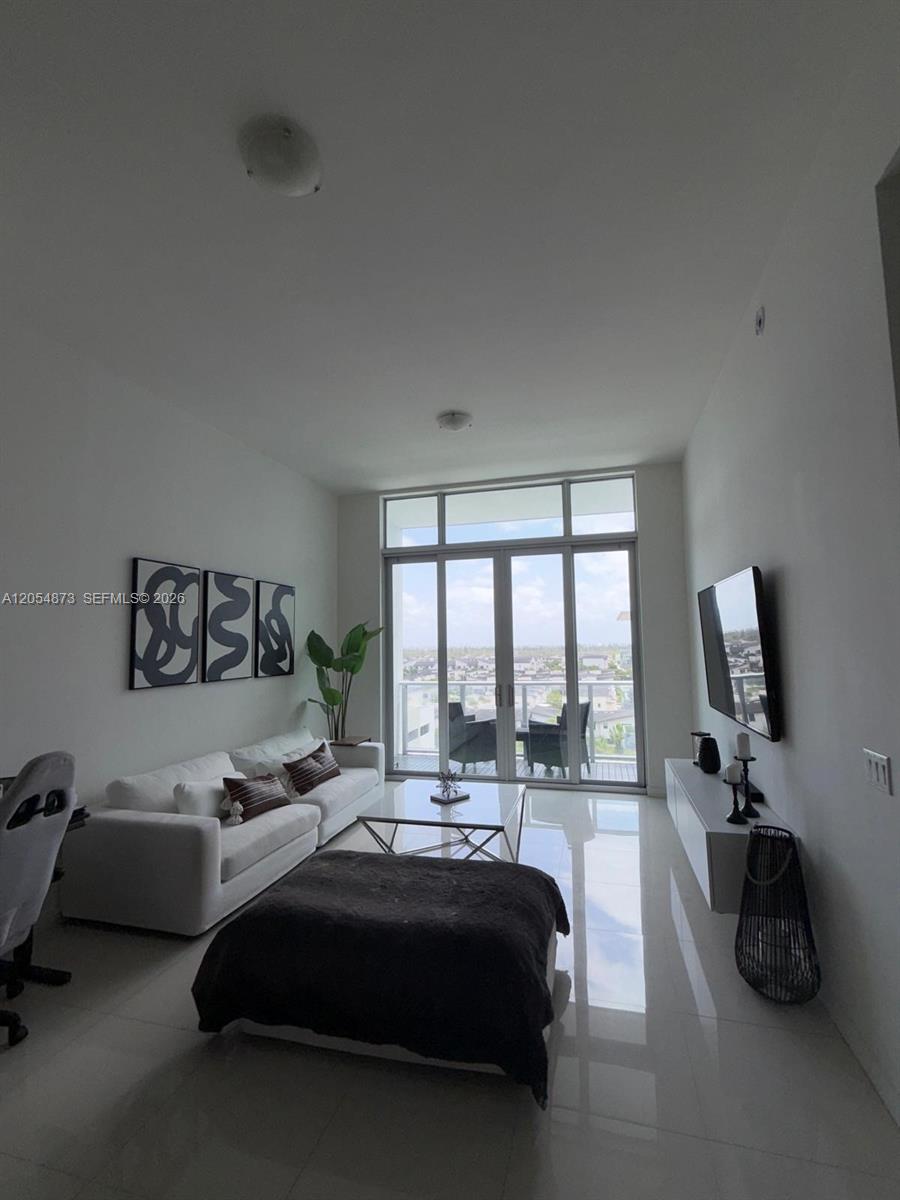 A modern living room features white tile floors, a white sofa, and floor-to-ceiling balcony windows — 7825 NW 107th Ave # 818, Doral FL 33178, DORAL, FL