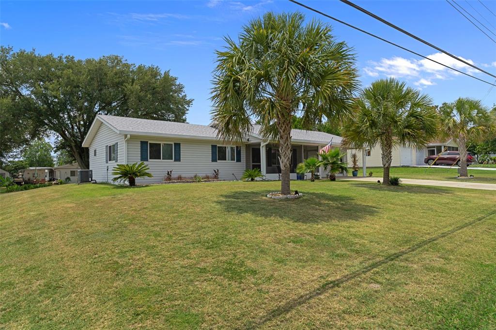 A single-story house with light gray siding and palm trees sits on a grassy lawn — 6264 SW 103RD STREET ROAD, OCALA, FL