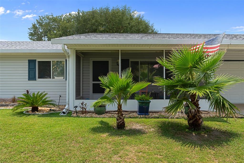 The exterior of a single-story house features a screened-in porch, palm trees, and a lawn — 6264 SW 103RD STREET ROAD, OCALA, FL