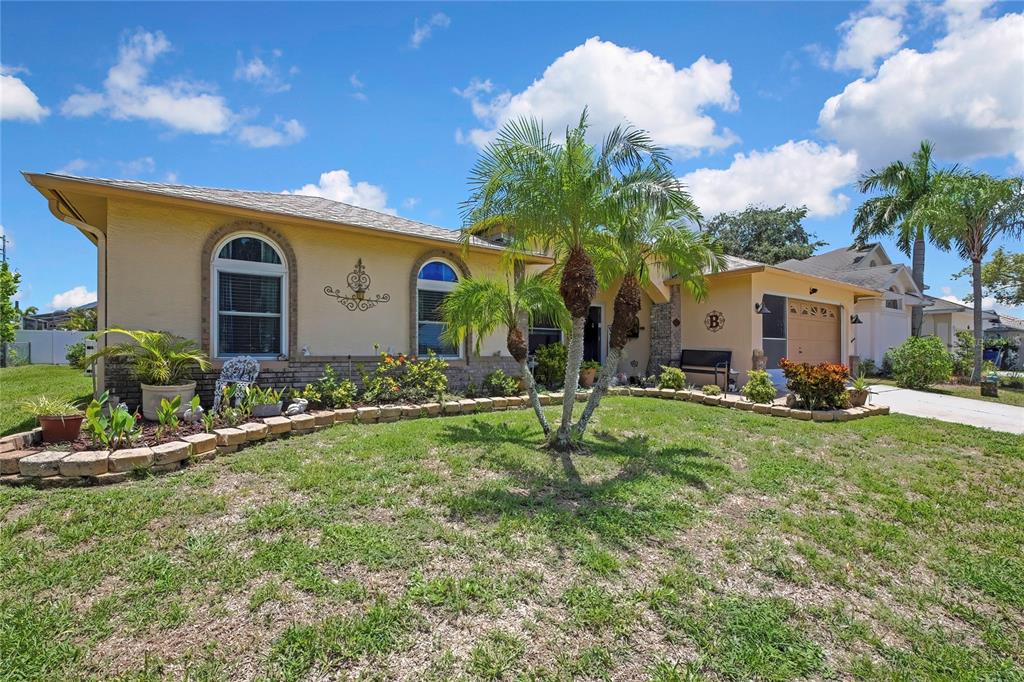 A single-story house with a tan stucco exterior, arched windows, and a front lawn — 5426 LA PLATA DRIVE, NEW PORT RICHEY, FL