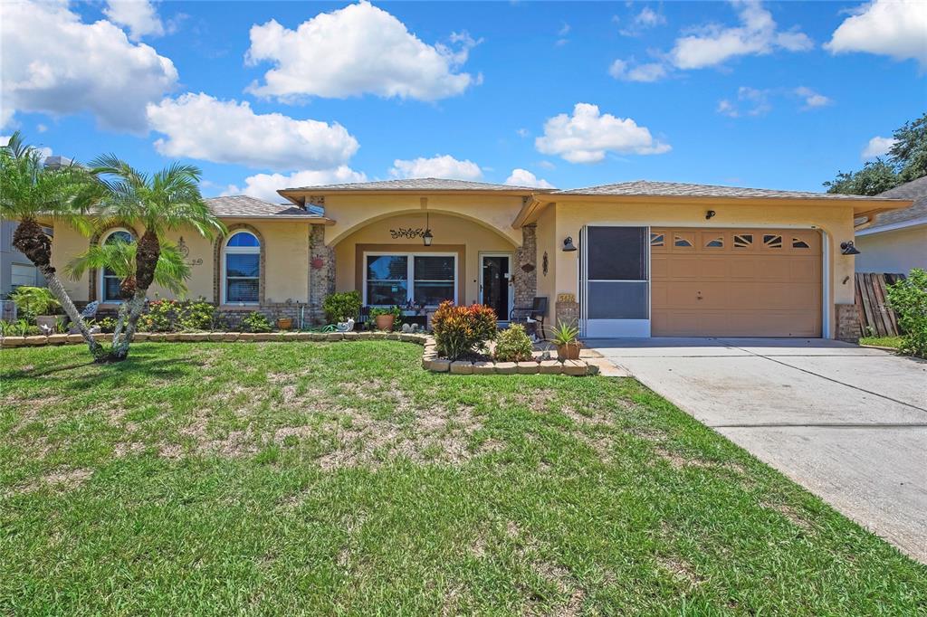 A single-story house with a tan stucco exterior, a two-car garage, and a front lawn — 5426 LA PLATA DRIVE, NEW PORT RICHEY, FL