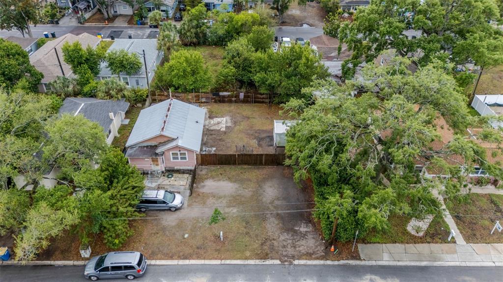 An aerial view shows a pink house with a metal roof and a vacant lot — 1127 ENGMAN STREET, CLEARWATER, FL