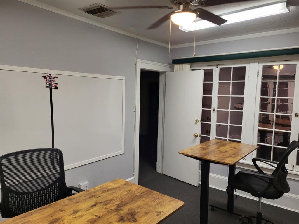 An office room features two wooden desks, black chairs, a whiteboard, and a ceiling fan — 457 S RIDGEWOOD AVENUE UNIT E, DAYTONA BEACH, FL