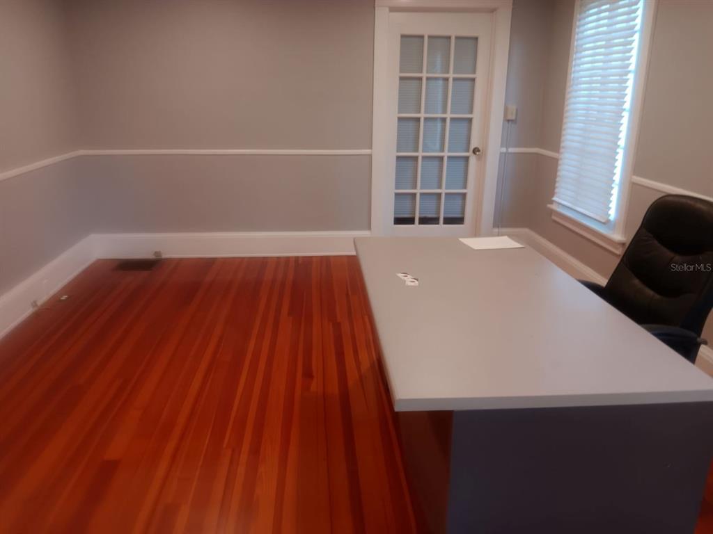 A home office features hardwood floors, gray walls with white trim, and a desk — 457 S RIDGEWOOD AVENUE UNIT E, DAYTONA BEACH, FL