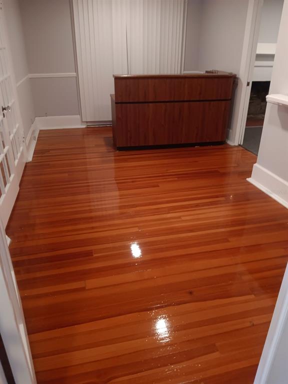 A room with polished hardwood floors and a wooden reception desk in front of blinds — 457 S RIDGEWOOD AVENUE UNIT E, DAYTONA BEACH, FL