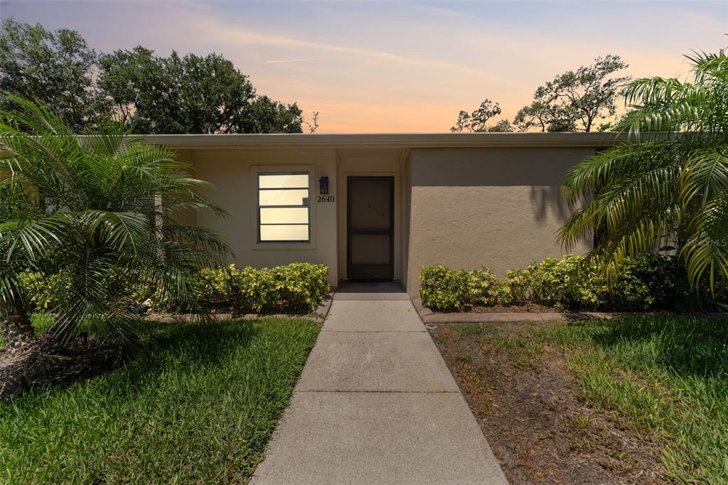 A concrete walkway leads to the front entrance of a single-story home with landscaping — 2640 WOODGATE LANE UNIT F6, SARASOTA, FL
