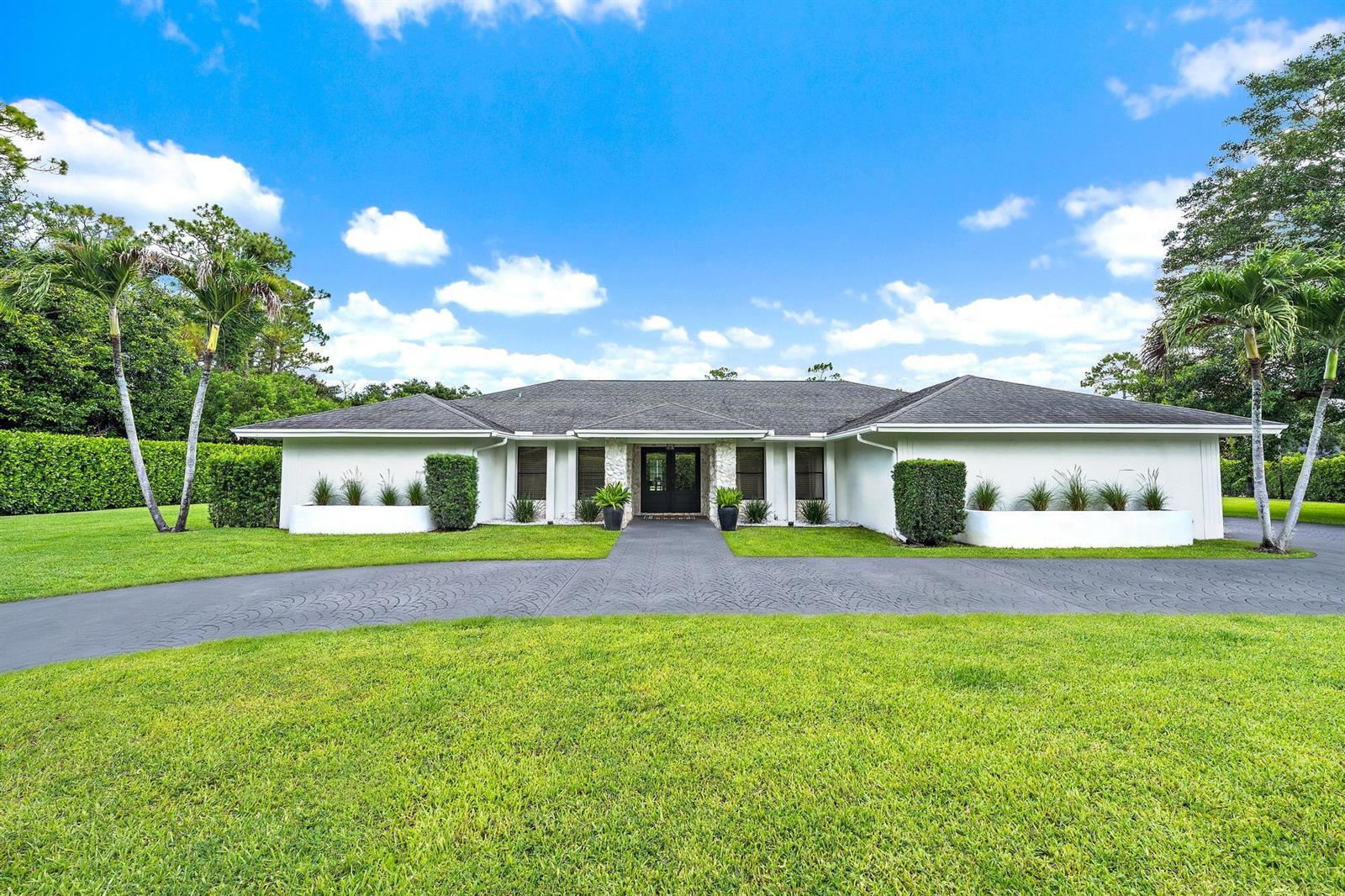 A single-story white house with a dark roof and a paved driveway sits on grass — 14039 Greentree Trail, Wellington FL 33414, WELLINGTON, FL