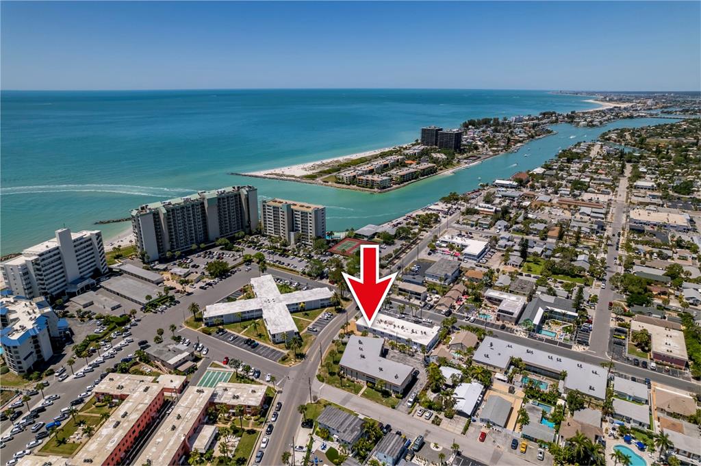 An aerial view shows a multi-story apartment complex with a red arrow pointing toward it — 7003 SUNSET WAY UNIT 3, ST PETE BEACH, FL