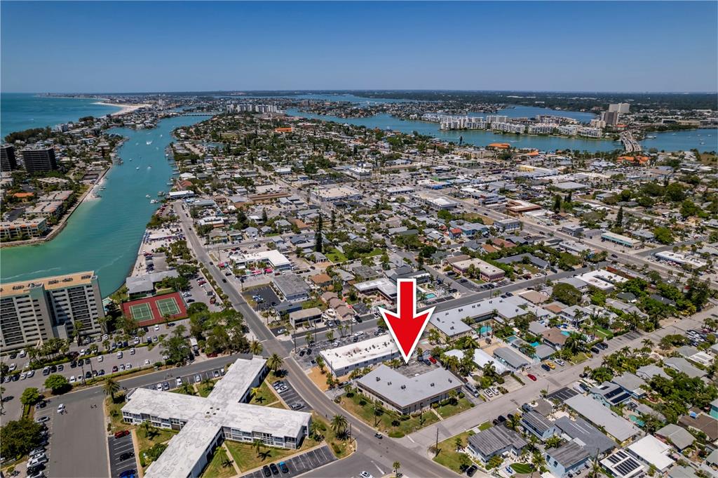An aerial view shows a multi-story apartment building marked by a red arrow — 7003 SUNSET WAY UNIT 3, ST PETE BEACH, FL