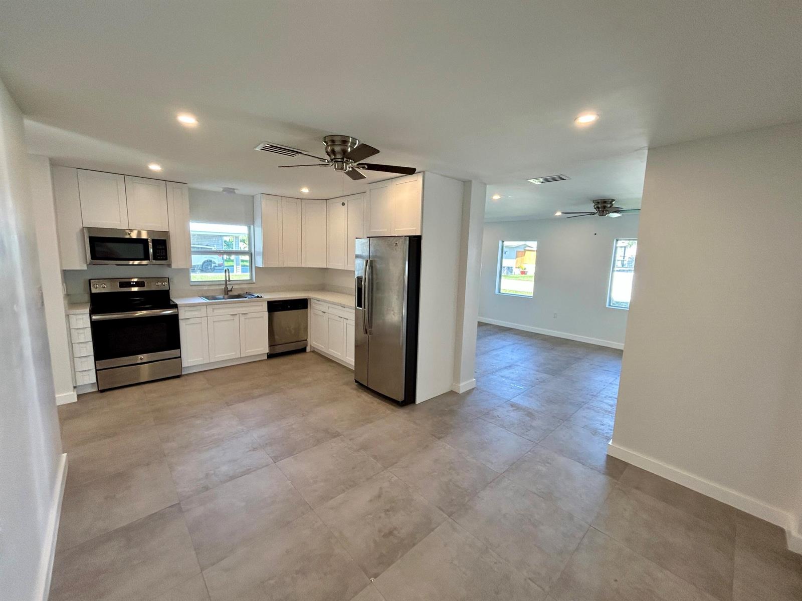 A kitchen with white cabinets and stainless steel appliances opens into a living area — 1134 6th Street, Okeechobee FL 34974, OKEECHOBEE, FL