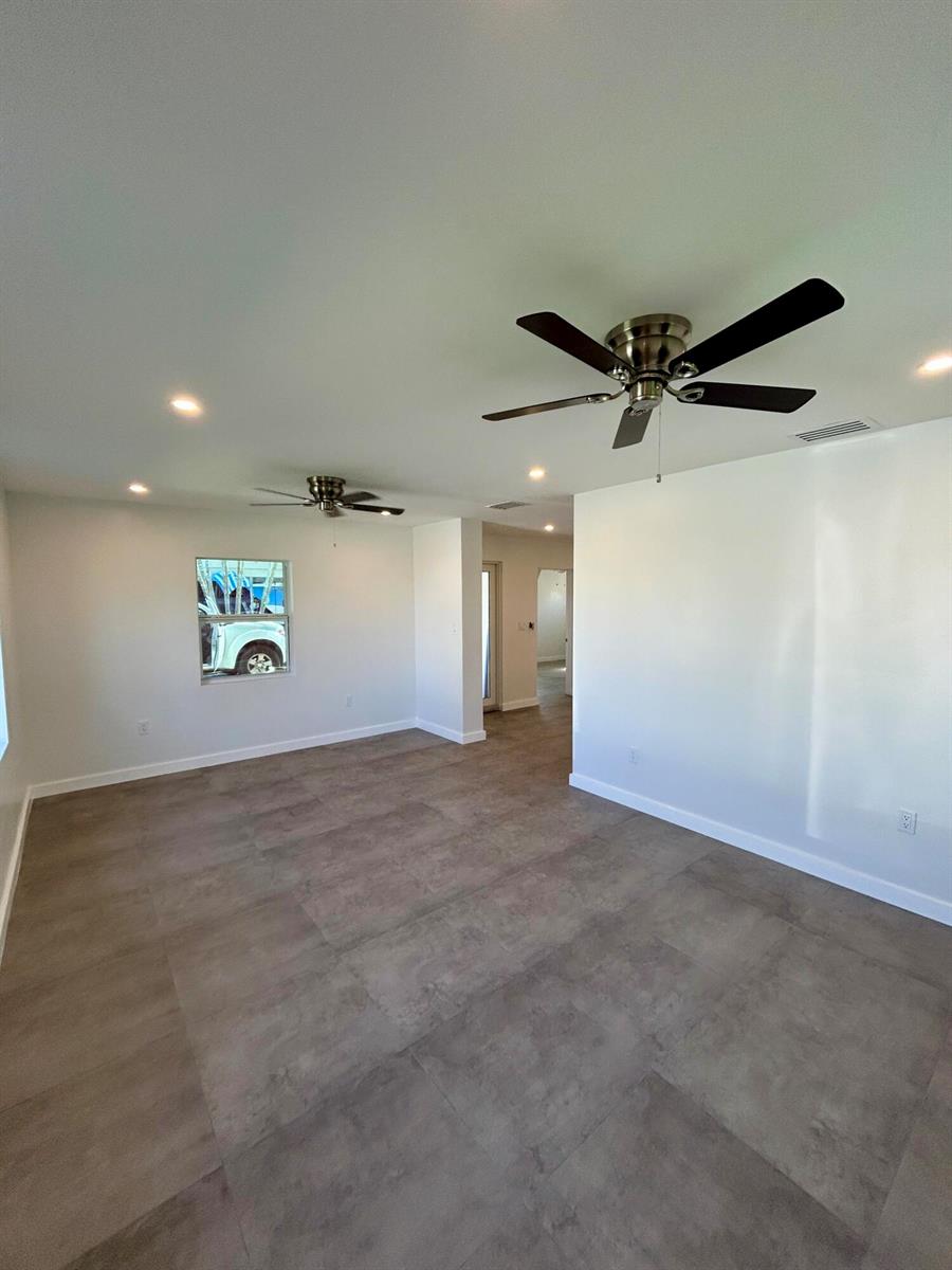 An empty room features gray tile flooring, white walls, recessed lighting, and two ceiling fans — 1134 6th Street, Okeechobee FL 34974, OKEECHOBEE, FL