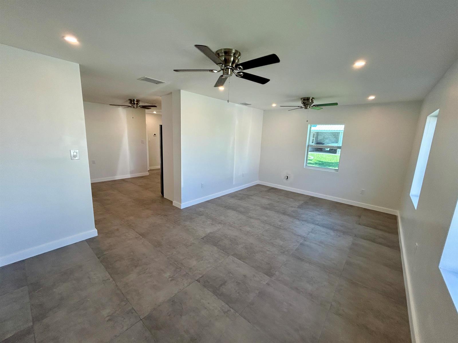 An open living area features large gray floor tiles, white walls, and three ceiling fans — 1134 6th Street, Okeechobee FL 34974, OKEECHOBEE, FL