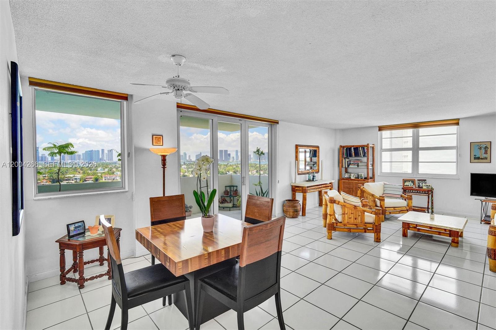 A bright living and dining area features white tile floors, bamboo furniture, and city views — 5 Island Ave # 12C, Miami Beach FL 33139, MIAMI BEACH, FL