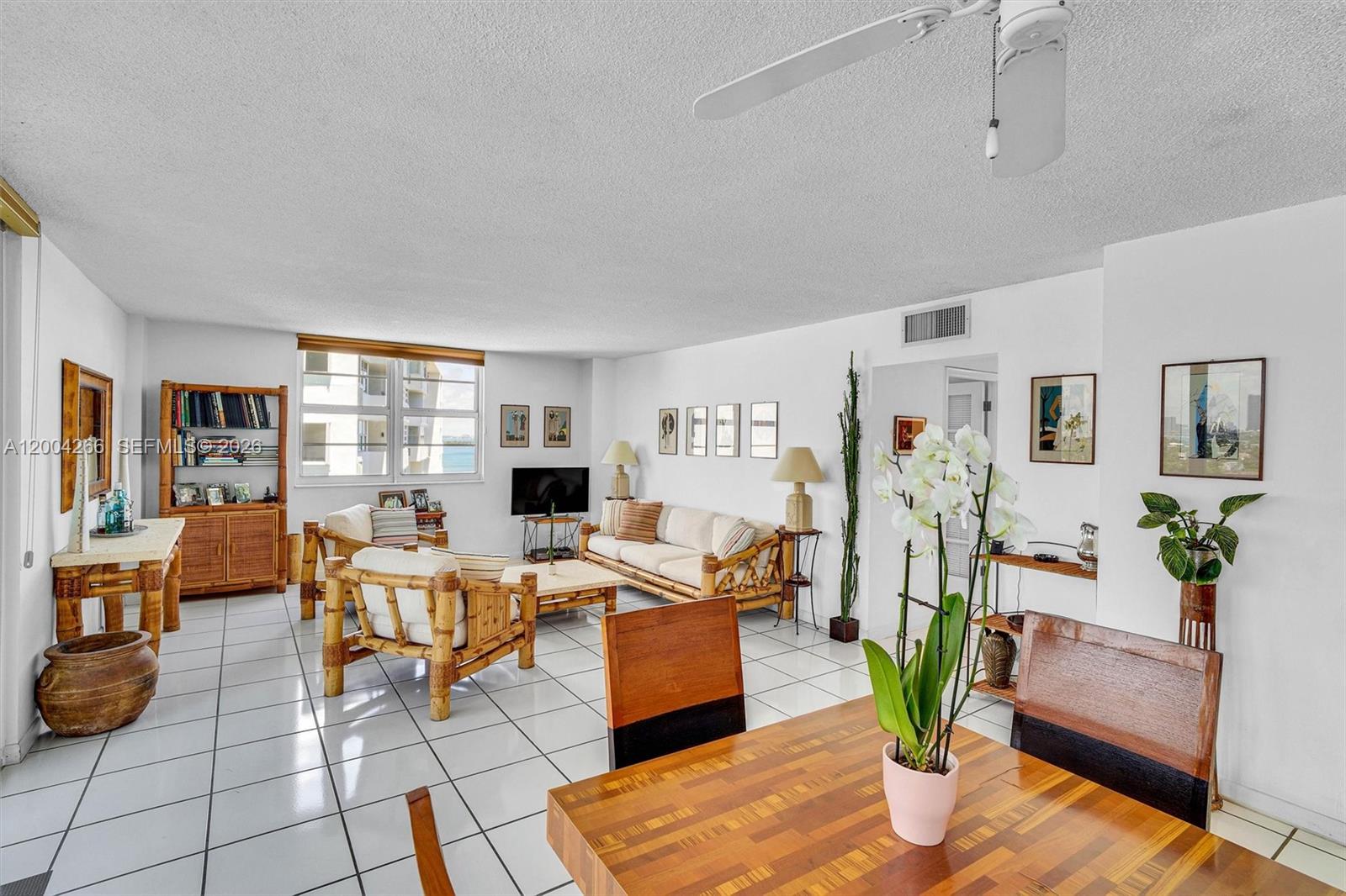 A living and dining area features white tile flooring, bamboo furniture, and a ceiling fan — 5 Island Ave # 12C, Miami Beach FL 33139, MIAMI BEACH, FL
