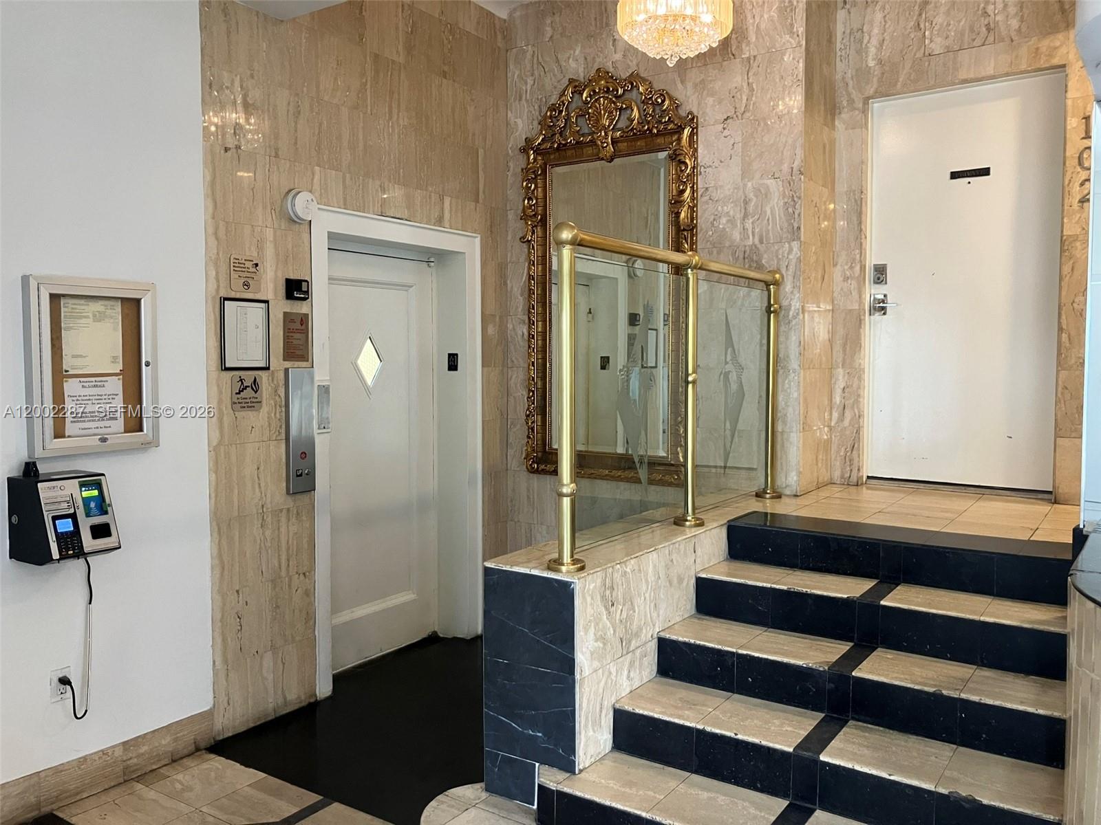An interior building lobby features marble walls, a gold-framed mirror, an elevator, and a staircase — 335 Ocean Dr # 306, Miami Beach FL 33139, MIAMI BEACH, FL