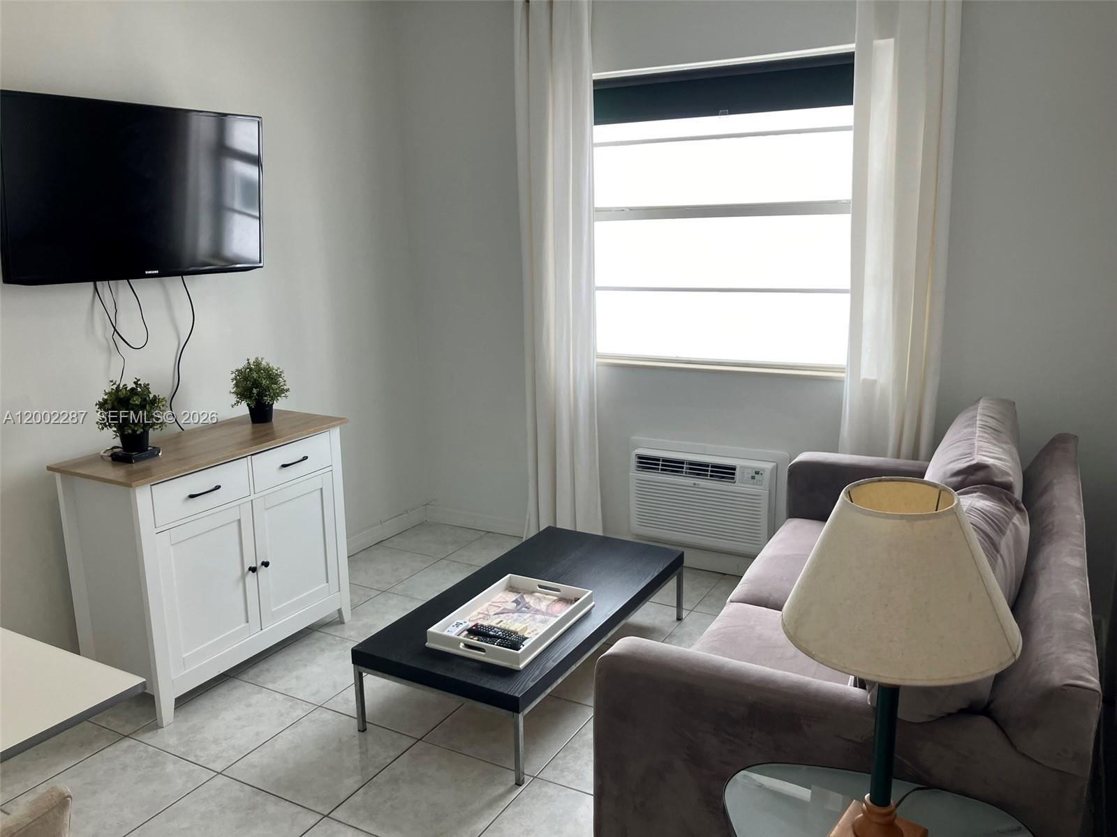 A living room features a wall-mounted television, a white cabinet, a coffee table, and a sofa — 335 Ocean Dr # 306, Miami Beach FL 33139, MIAMI BEACH, FL
