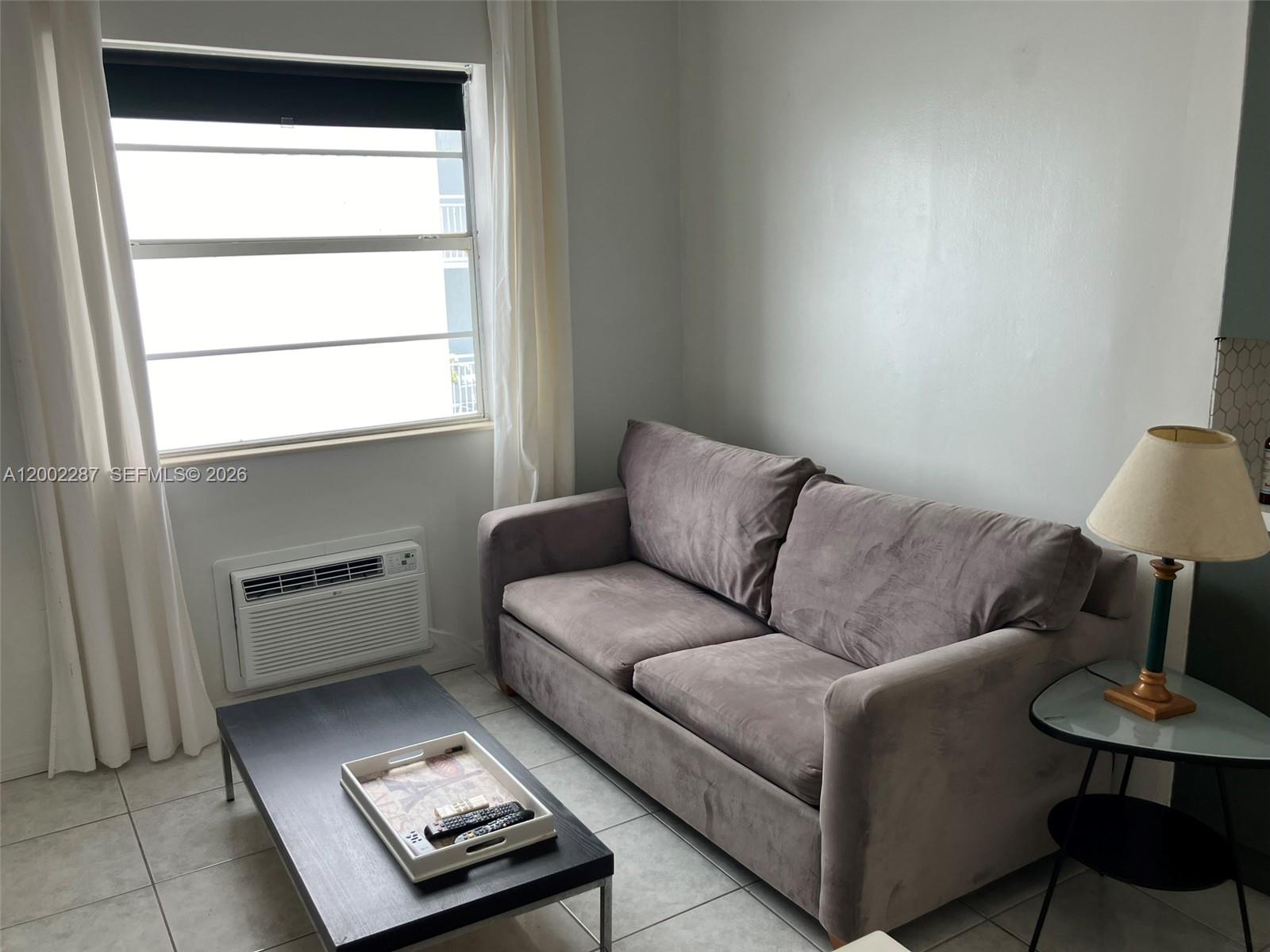 A living room features a gray sofa, a black coffee table, and a window unit air conditioner — 335 Ocean Dr # 306, Miami Beach FL 33139, MIAMI BEACH, FL