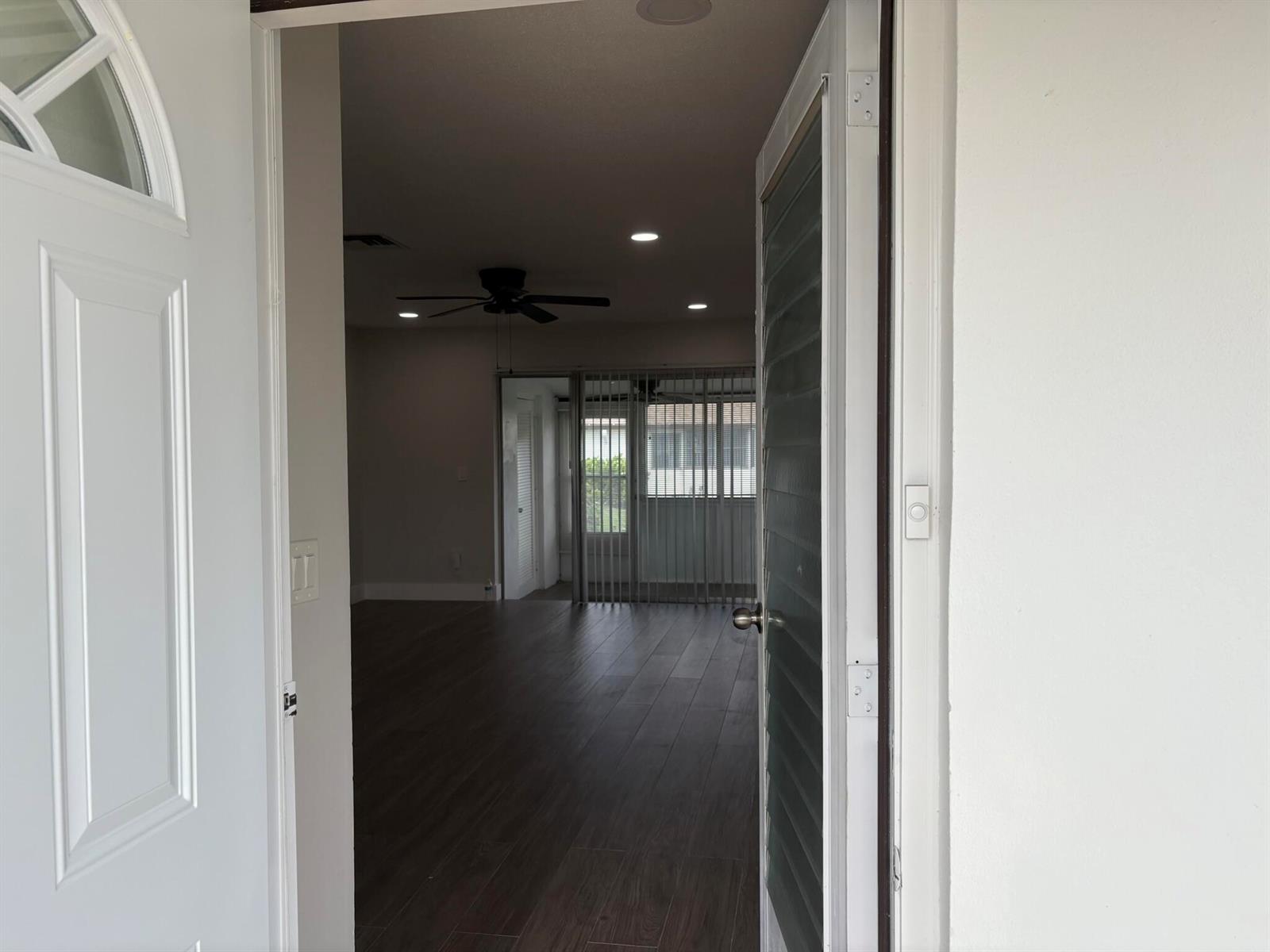 An open front door reveals a living area with wood-look flooring and a ceiling fan — 2930 CROSLEY Drive E # J, West Palm Beach FL 33415, WEST PALM BEACH, FL