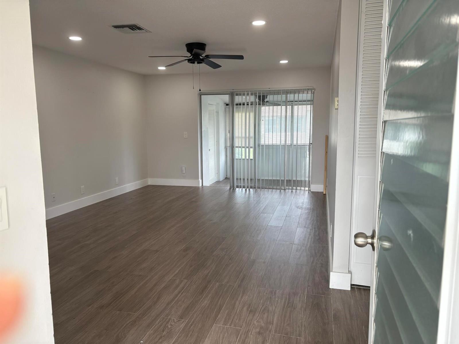 An empty living room features wood-look tile flooring, recessed lighting, a ceiling fan, and vertical blinds — 2930 CROSLEY Drive E # J, West Palm Beach FL 33415, WEST PALM BEACH, FL