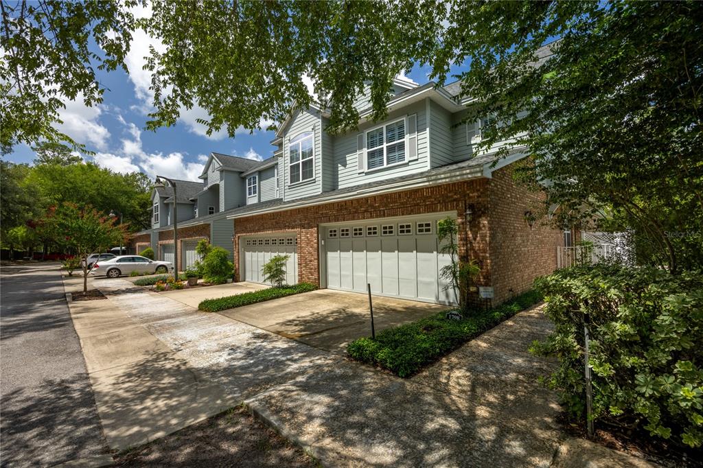 A multi-story townhouse exterior features brick and siding, a two-car garage, and surrounding trees — 1798 NW 34TH STREET UNIT 12, GAINESVILLE, FL