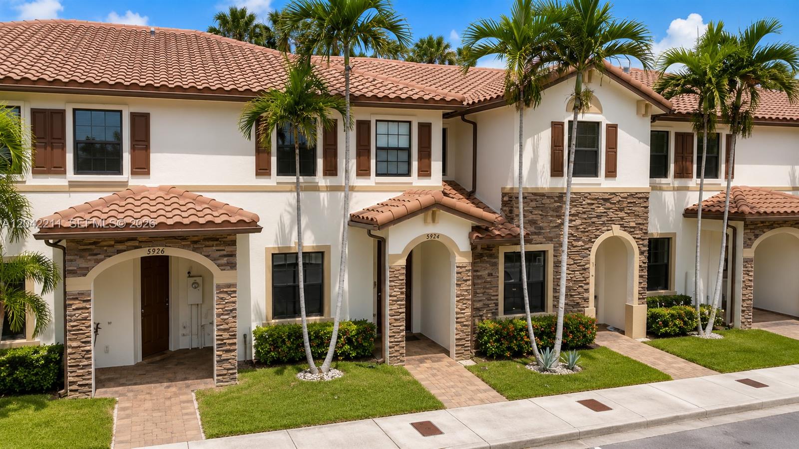A row of two-story townhomes features stucco walls, stone accents, and brown tile roofs — 8954 W 35th Way, Hialeah FL 33018, HIALEAH, FL
