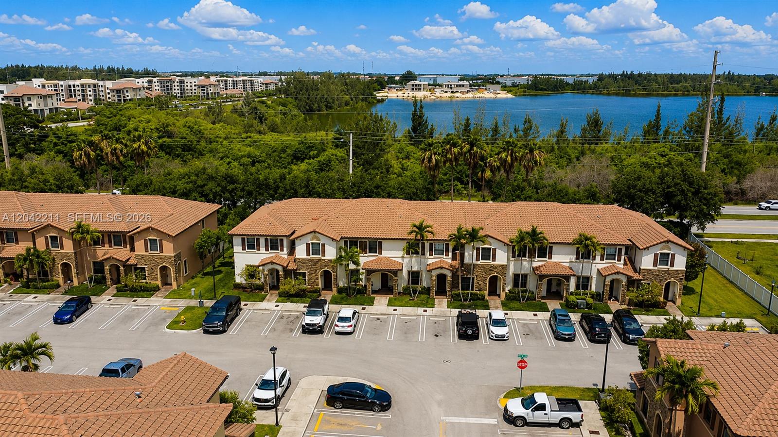 An aerial view shows a multi-unit residential building with a parking lot and lake — 8954 W 35th Way, Hialeah FL 33018, HIALEAH, FL