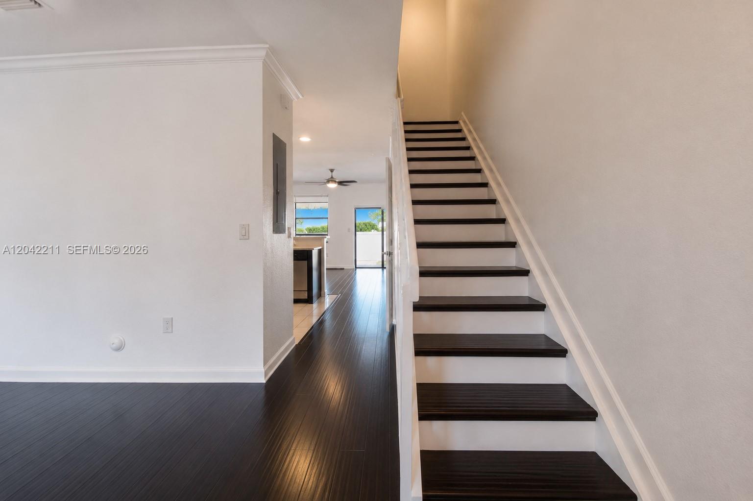 A staircase with dark wood treads and white risers leads upward beside a hallway — 8954 W 35th Way, Hialeah FL 33018, HIALEAH, FL