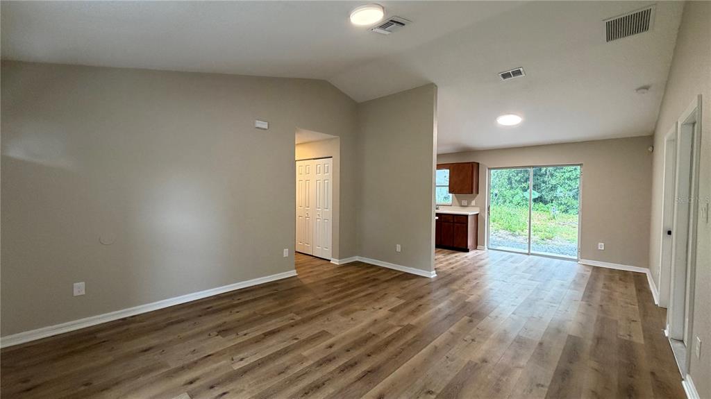 An open-concept living area features light-colored walls, wood-look flooring, and a sliding glass door — 2231 WATER STREET, SANFORD, FL