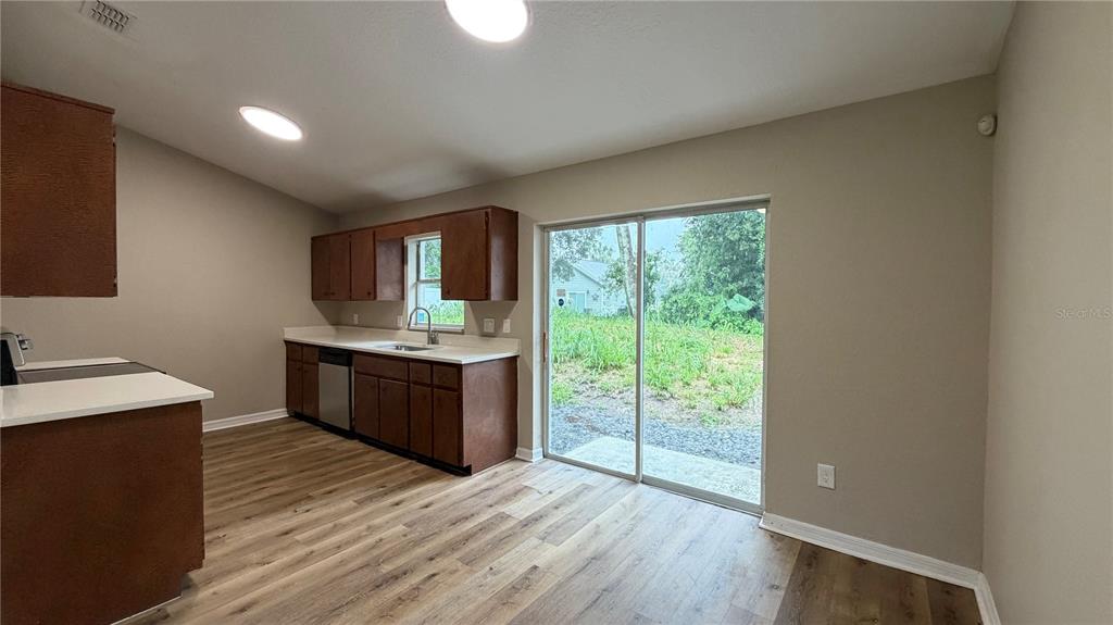A kitchen with dark wood cabinets, white countertops, and sliding glass doors to the backyard — 2231 WATER STREET, SANFORD, FL