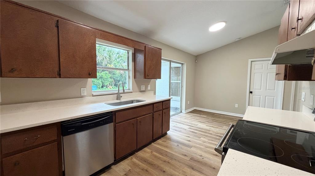 A kitchen features wood cabinets, white countertops, stainless steel appliances, and wood-look flooring — 2231 WATER STREET, SANFORD, FL