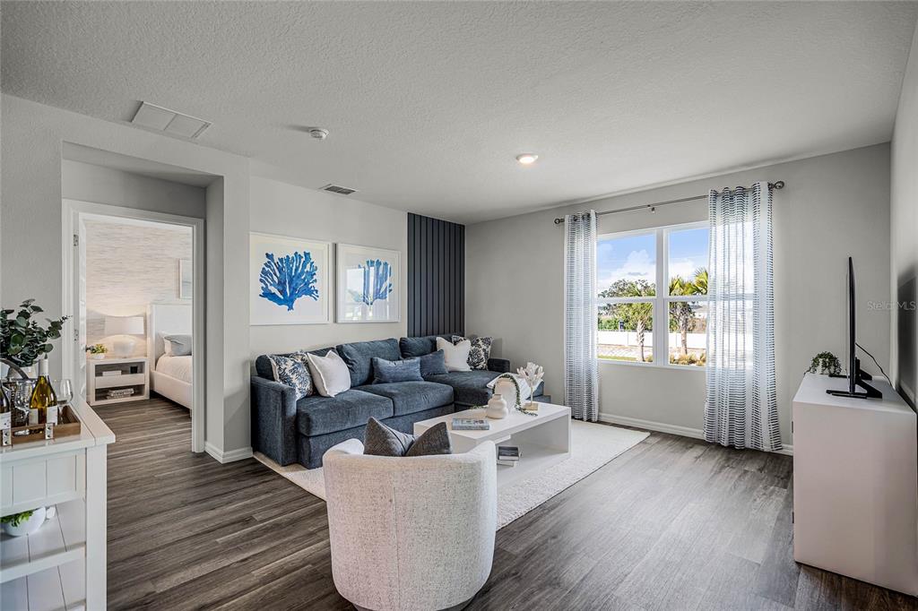 A living room features a blue sectional sofa, a white armchair, and wood-look flooring — 3594 RODEN ROAD, HAINES CITY, FL