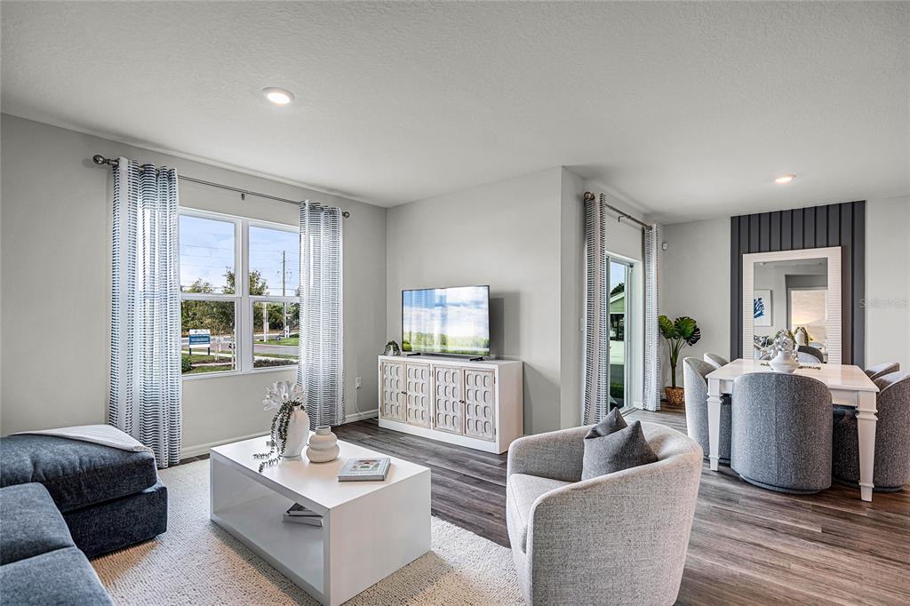 A living room and dining area feature light gray walls, wood-look flooring, and modern furnishings — 3594 RODEN ROAD, HAINES CITY, FL