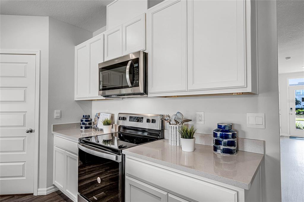 A kitchen features white cabinets, stainless steel appliances, and light-colored quartz countertops — 3594 RODEN ROAD, HAINES CITY, FL