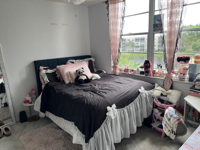 A bedroom features a dark bed with a ruffled white skirt and pink curtains — 9330 Lagoon Place # 406, Davie FL 33324, DAVIE, FL