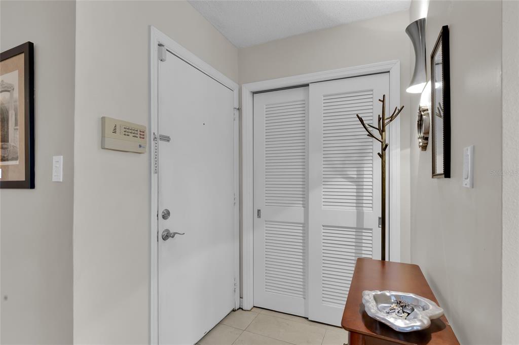 An entryway features a white front door, a louvered closet, and a small wooden table — 500 NEWELL HILL RD UNIT 110D, LEESBURG, FL