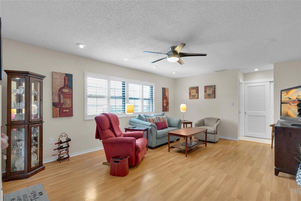 A living room features light wood flooring, a ceiling fan, and a red recliner — 500 NEWELL HILL RD UNIT 110D, LEESBURG, FL