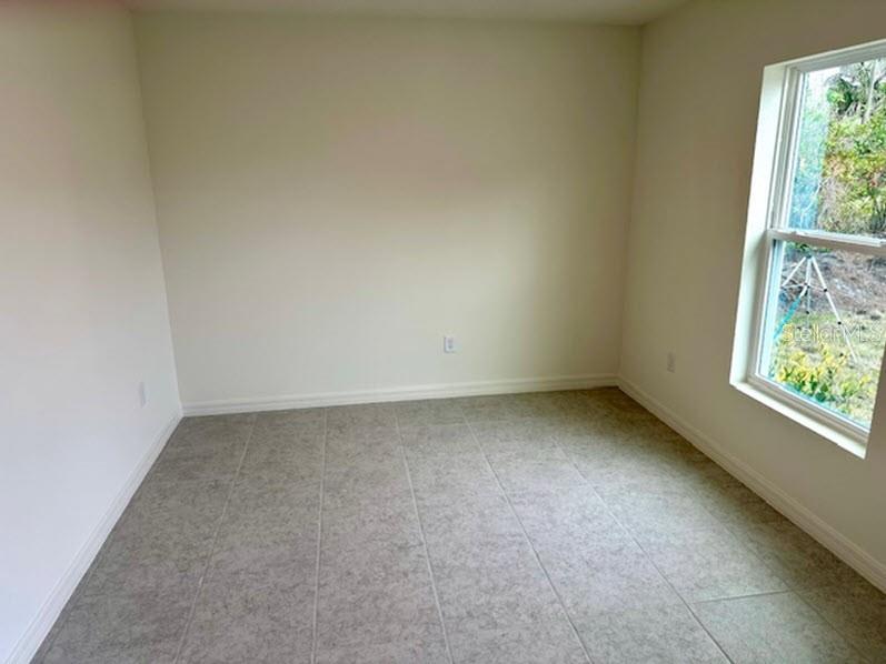 An empty room with light-colored walls, large square floor tiles, and a single window — 91 BRESSLER LANE, PALM COAST, FL
