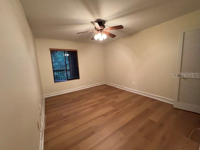 An empty bedroom with light wood-look flooring, a ceiling fan, and a window with blinds — 11722 RAINTREE LAKE LANE UNIT C, TAMPA, FL