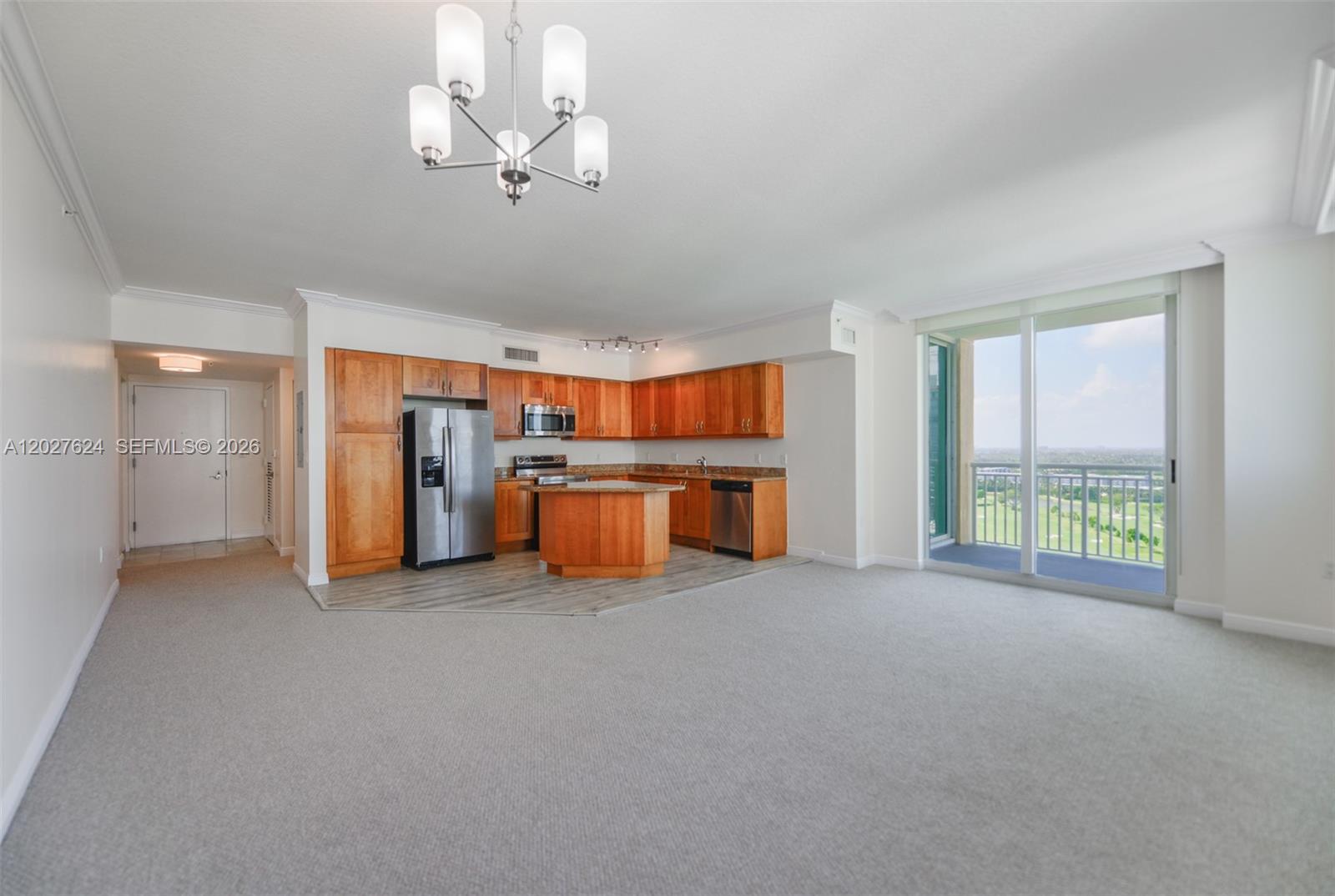 An open-concept kitchen with wood cabinets and a balcony overlooks a golf course — 1745 E Hallandale Beach Blvd # 1903W, Hallandale Beach FL 33009, HALLANDALE BEACH, FL