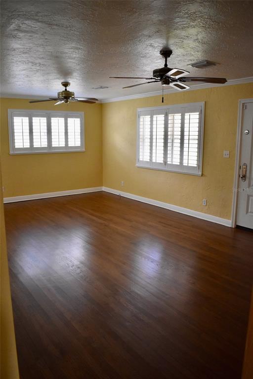 An empty room with yellow walls, dark hardwood floors, and two ceiling fans — 2200 E GORE STREET, ORLANDO, FL