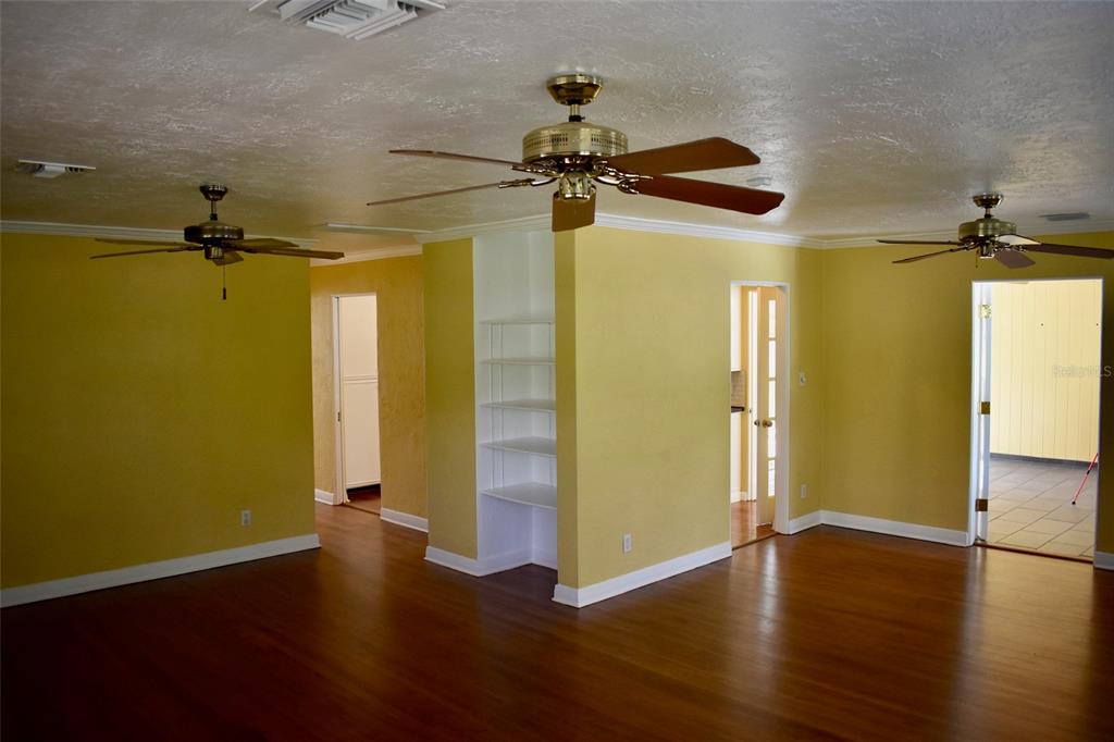 A living room with yellow walls, hardwood floors, three ceiling fans, and built-in white shelving — 2200 E GORE STREET, ORLANDO, FL