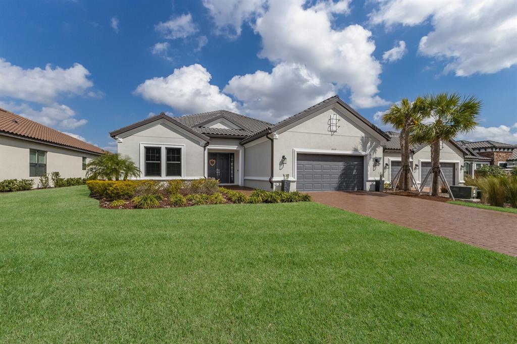 A single-story house with a gray garage, tiled roof, and a brick driveway — 5510 PANELLA COURT, PALMETTO, FL