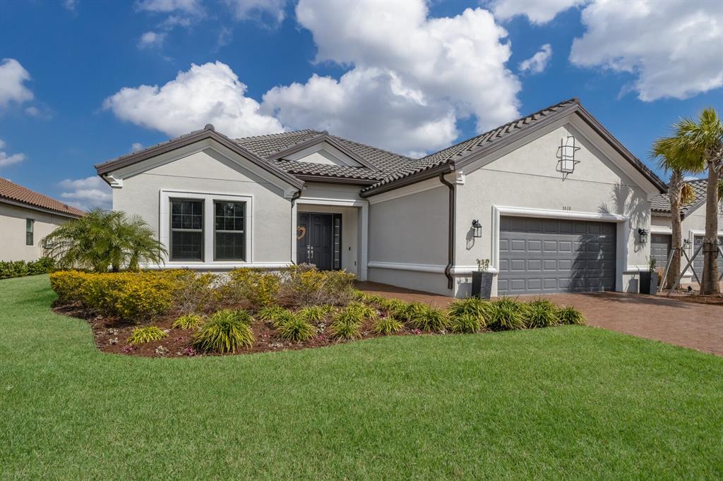A single-story house with a gray garage, tiled roof, and landscaped front yard — 5510 PANELLA COURT, PALMETTO, FL