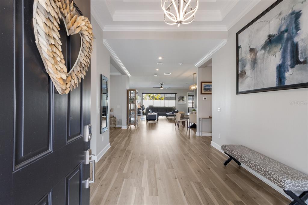 A bright entryway features light wood flooring, a patterned bench, and a view into the home — 5510 PANELLA COURT, PALMETTO, FL