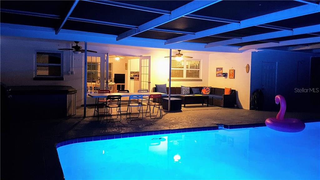 A covered patio features a swimming pool, dining area, and outdoor seating at night — 2205 59TH STREET S, GULFPORT, FL