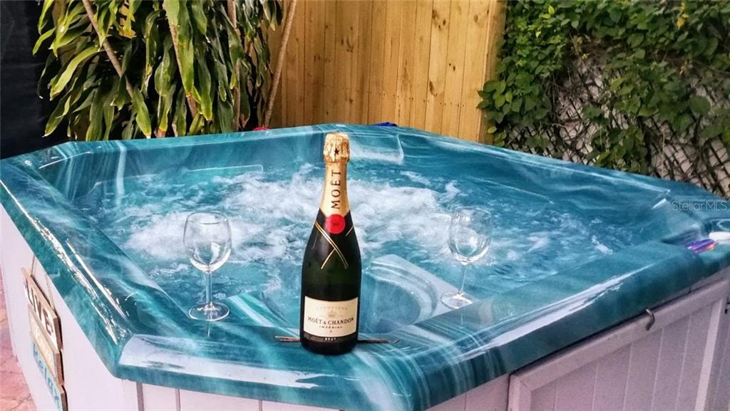 A hot tub with a bottle of champagne and two glasses sits on a patio — 2205 59TH STREET S, GULFPORT, FL