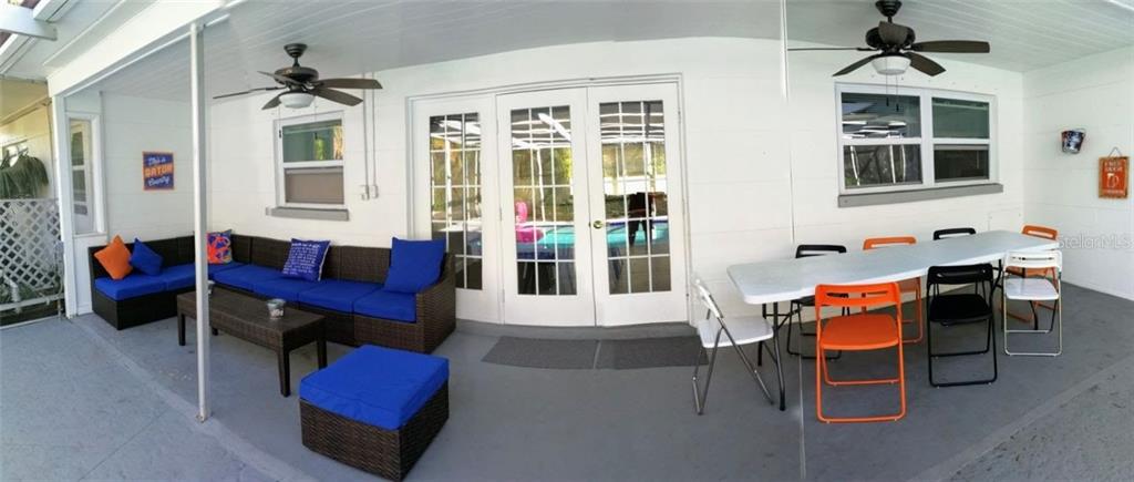 A covered patio features a wicker sectional sofa, a dining table with chairs, and ceiling fans — 2205 59TH STREET S, GULFPORT, FL